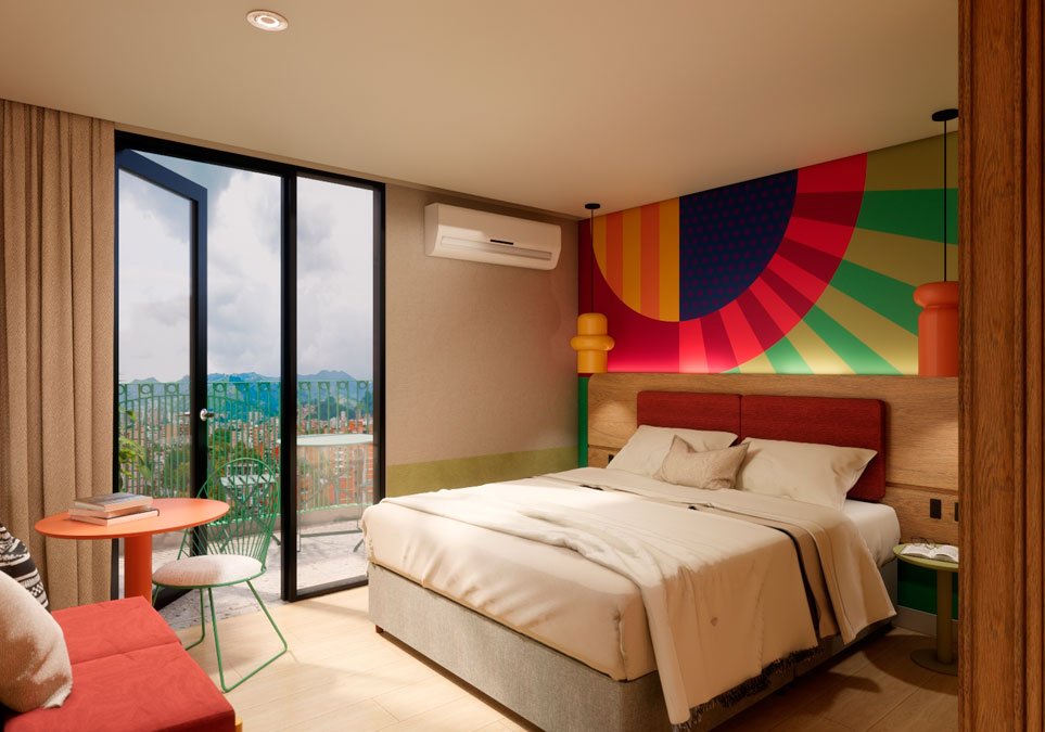 Habitación moderna del hotel Ibis Styles Medellín con balcón y vista panorámica a la ciudad