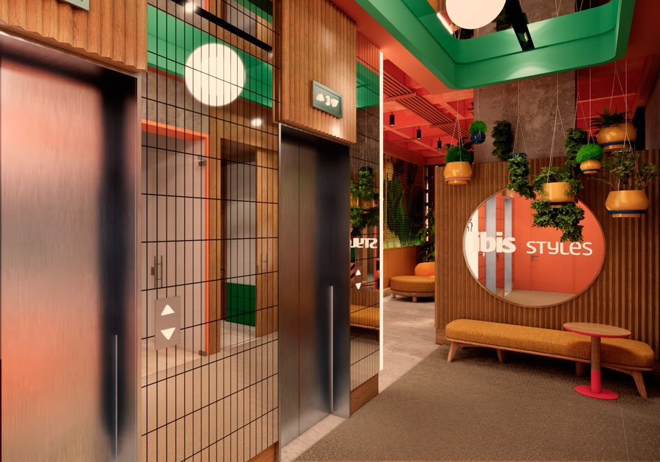 Zona de lobby y ascensores del hotel Ibis Styles Medellín con decoración moderna y colorida