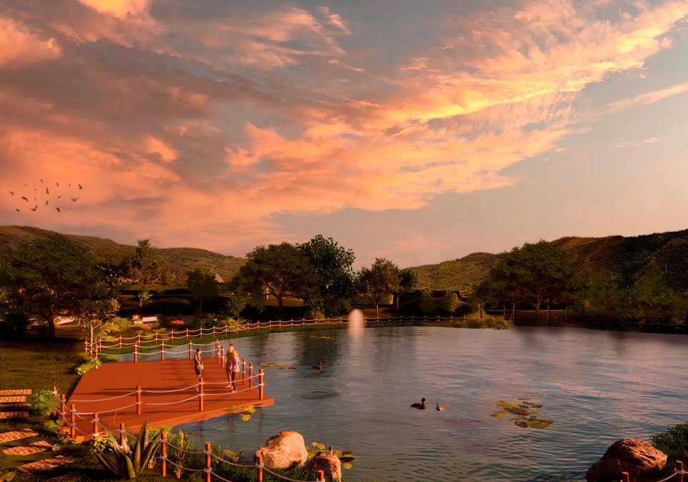 Lago central del proyecto Caña Dulce con muelle de madera, zonas verdes y vista a las montañas al atardecer.